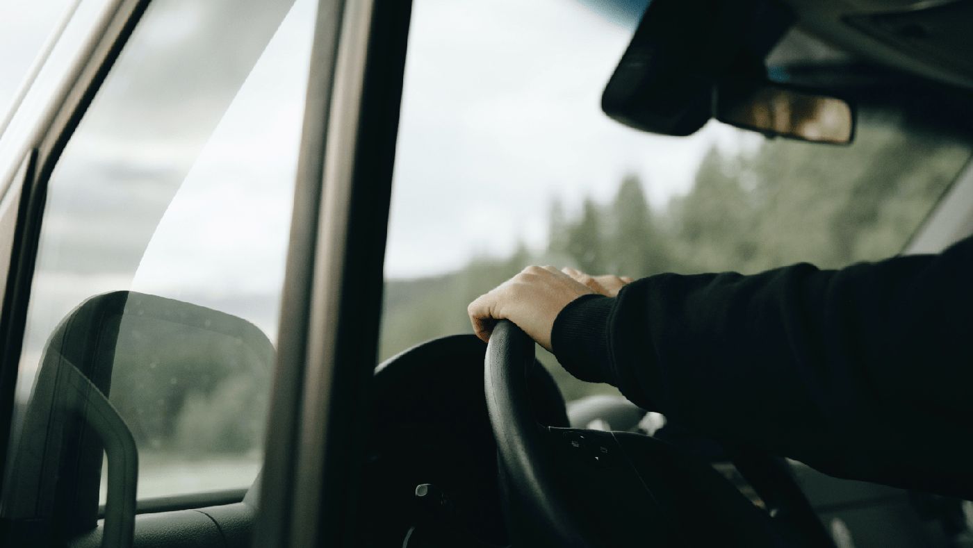Persona al volante de una furgoneta camper, disfrutando de un viaje ecológico por carretera.