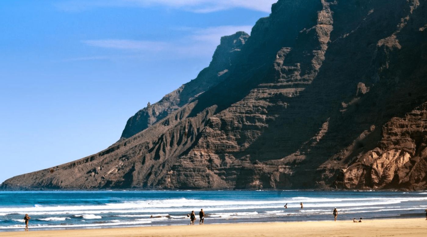 Playa de Famara en Lanzarote, conocida por sus impresionantes acantilados y su ambiente perfecto para surfear y desconectar.