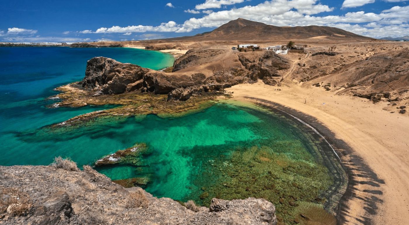 Vista de la playa de Papagayo en Lanzarote con aguas cristalinas y arena dorada, uno de los destinos más espectaculares de la isla.