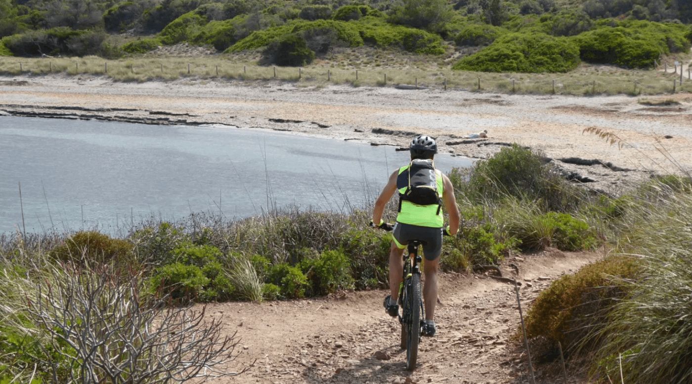 Persona pedaleando por el Camí de Cavalls en Menorca, una ruta popular para recorrer la isla.