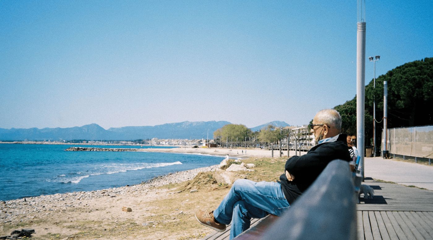Hombre sentado en un banco disfrutando de las vistas del mar en Cambrils, un lugar ideal para hacer una pausa.