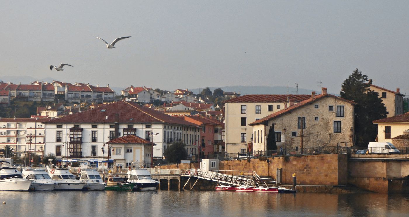 Puerto con barcos y casas tradicionales en un pueblo costero de Cantabria: San Vicente de la Barquera.
