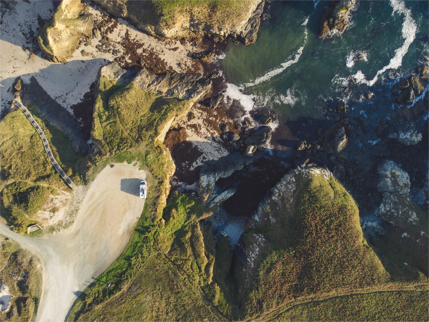 Vista panorámica de las Islas Cíes con una furgoneta camper en miniatura, explorando la costa gallega.