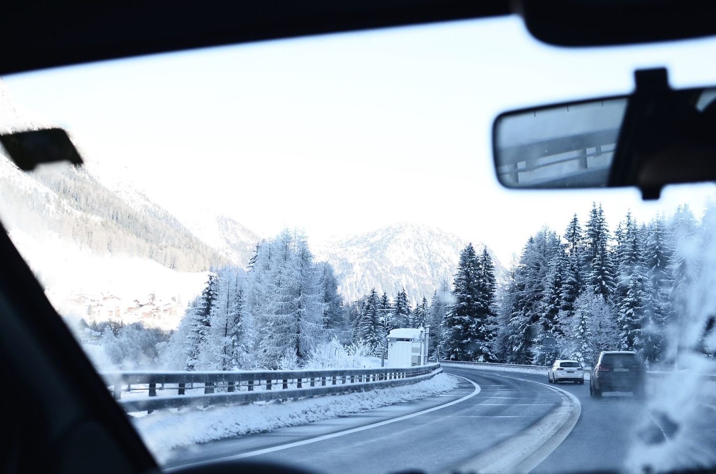 Vista desde el interior de una furgoneta camper mientras circula por una carretera nevada, ideal para viajar en invierno.