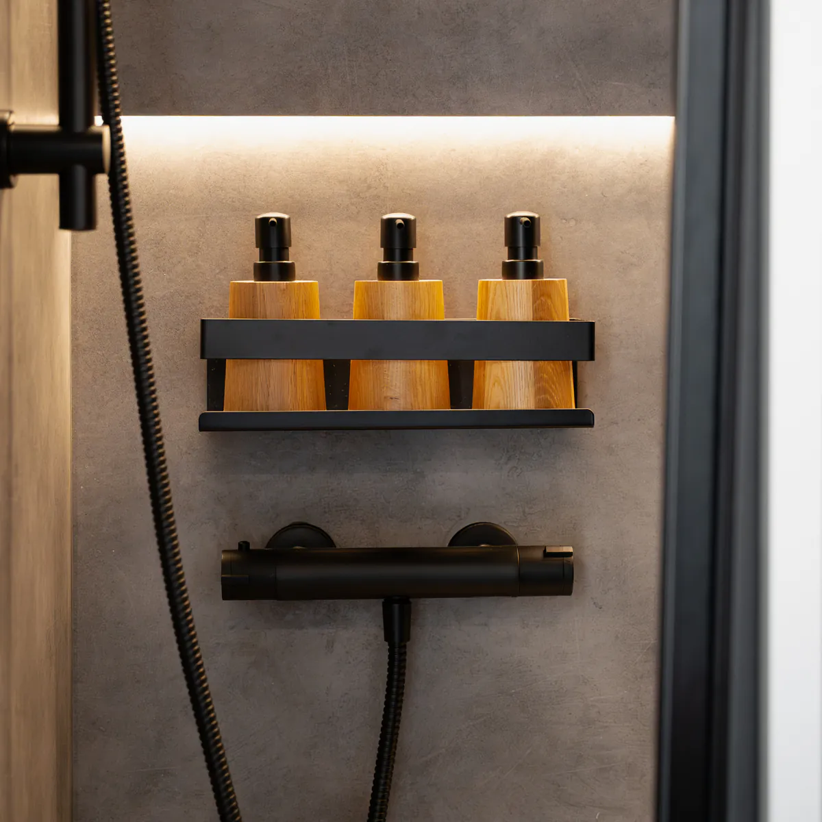 The shower, with black taps and bamboo dispensers