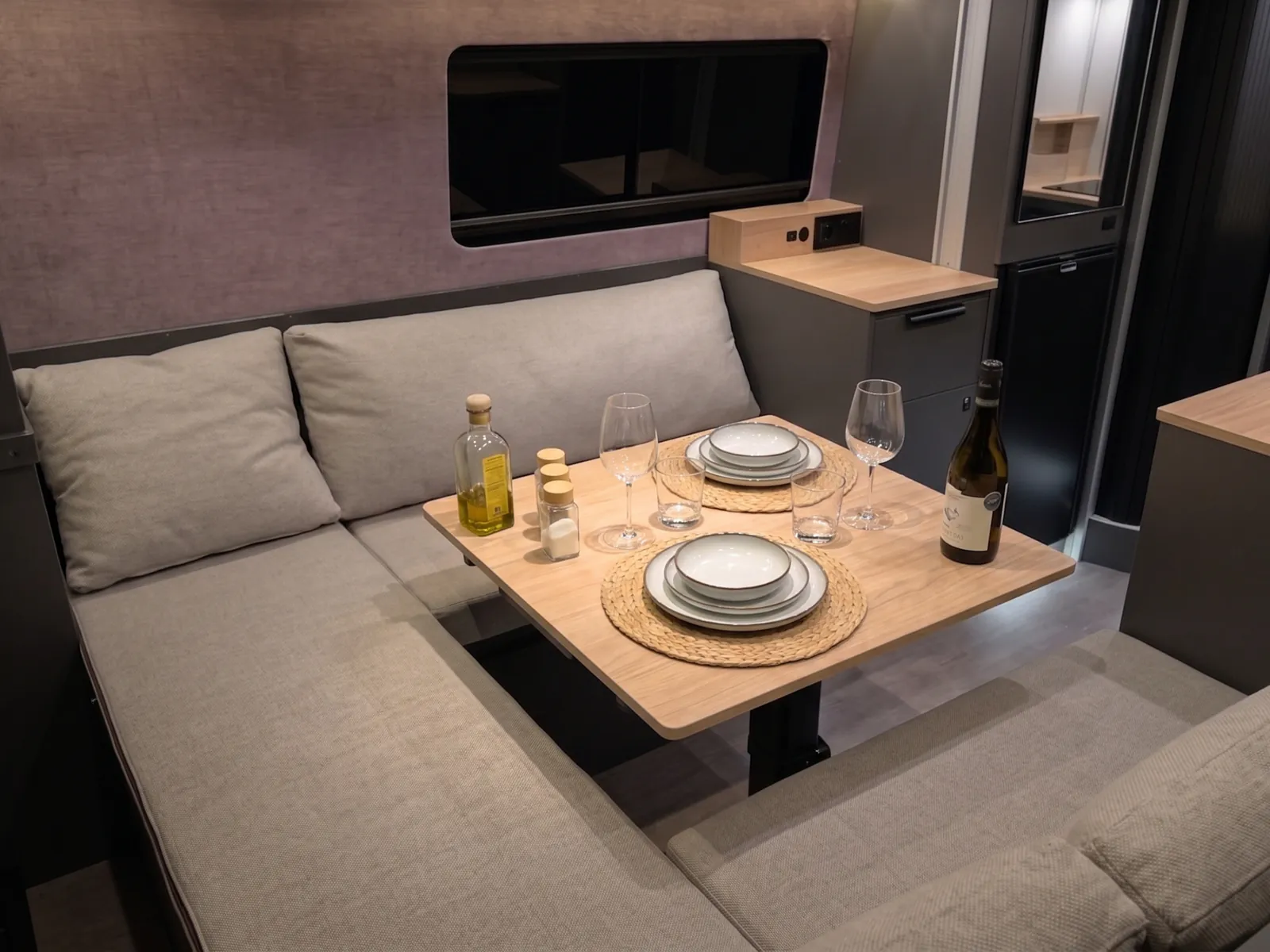 The lounge with the table laid for two, and the L-shaped sofa beside the window