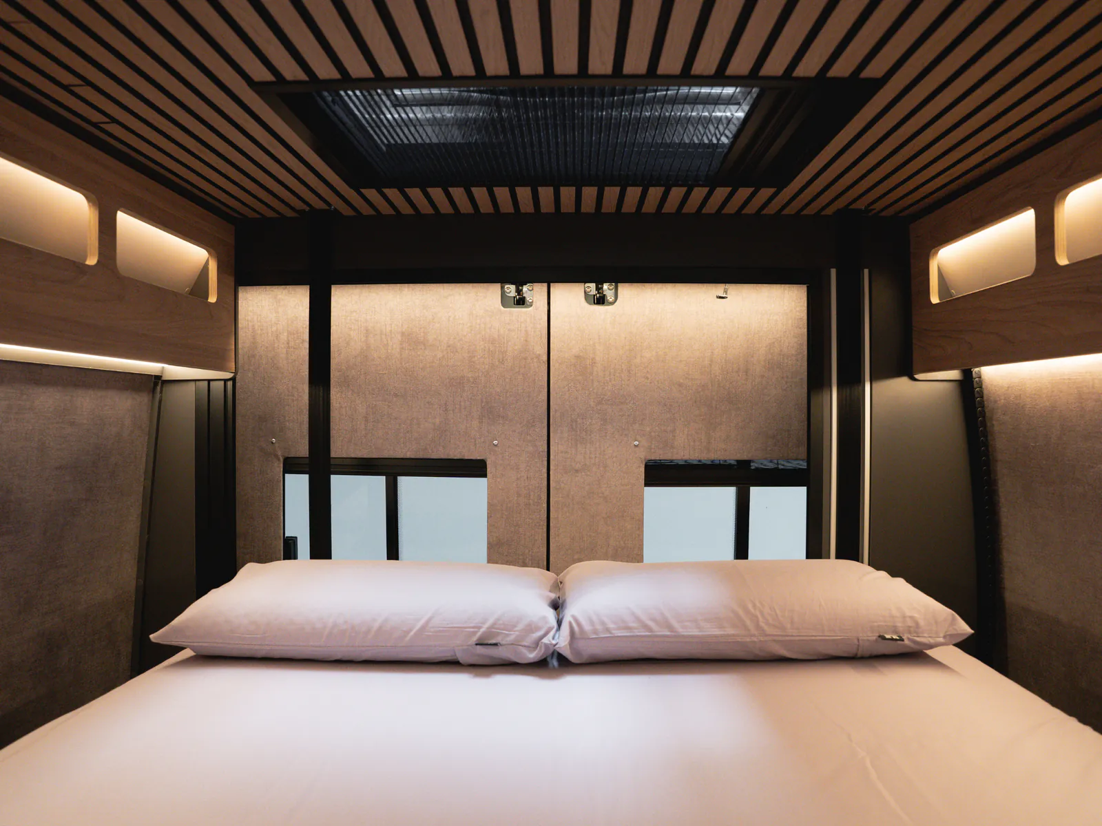 The fixed rear double bed, made up, under the slatted wooden ceiling